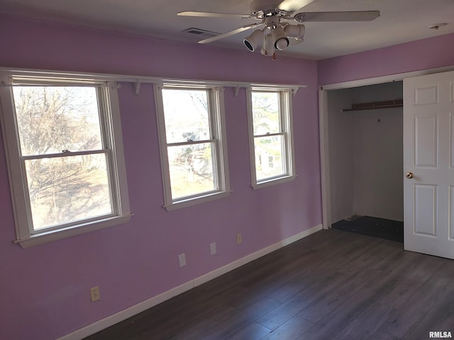 unfurnished bedroom featuring visible vents, dark wood-type flooring, ceiling fan, baseboards, and a closet