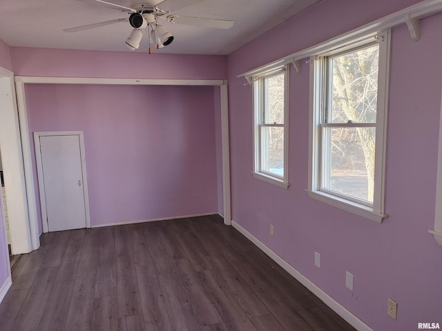 unfurnished room featuring baseboards, dark wood-type flooring, and a ceiling fan