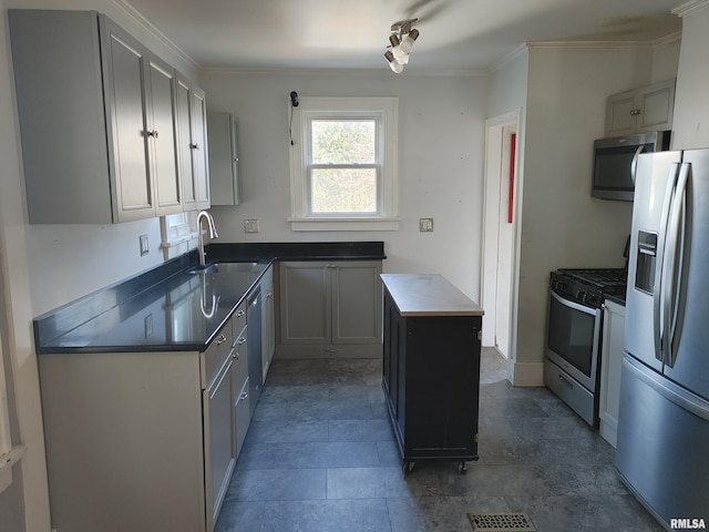 kitchen with a sink, a kitchen island, dark countertops, stainless steel appliances, and crown molding