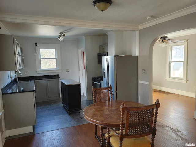 dining space featuring a wealth of natural light, arched walkways, wood-type flooring, and ornamental molding