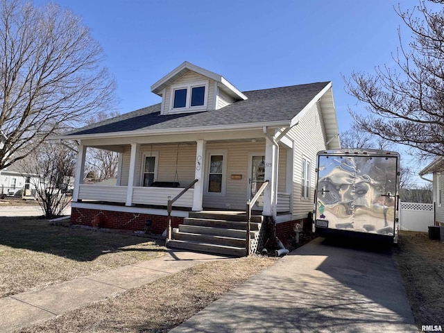 view of front of home with roof with shingles, a porch, and driveway