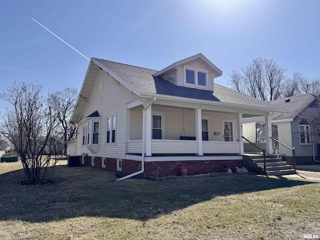 view of front of home with covered porch, a shingled roof, and a front yard