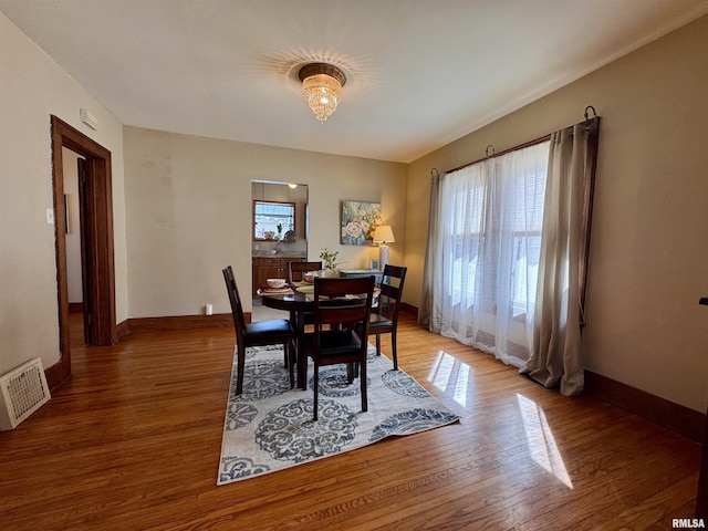 dining room with visible vents, light wood-style flooring, an inviting chandelier, and baseboards