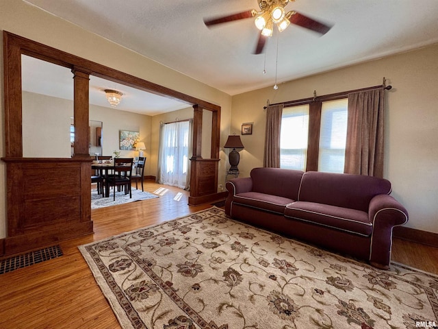 living room with decorative columns, a healthy amount of sunlight, ceiling fan, and light wood finished floors