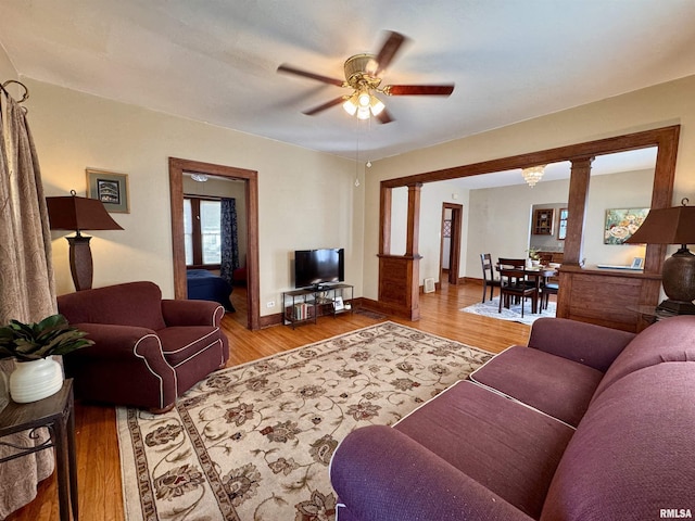 living room with light wood-style flooring, baseboards, and a ceiling fan