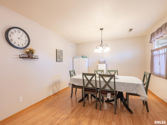 dining room featuring visible vents, baseboards, light wood-style floors, and an inviting chandelier