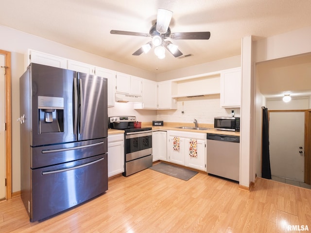 kitchen with a sink, light wood finished floors, appliances with stainless steel finishes, and white cabinetry