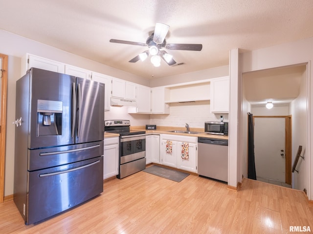 kitchen featuring visible vents, light wood-type flooring, stainless steel appliances, white cabinetry, and a sink