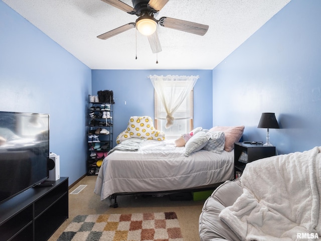 carpeted bedroom featuring visible vents, a textured ceiling, and a ceiling fan