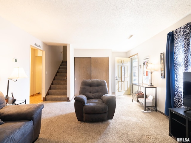 living room with stairs, a textured ceiling, baseboards, and light carpet