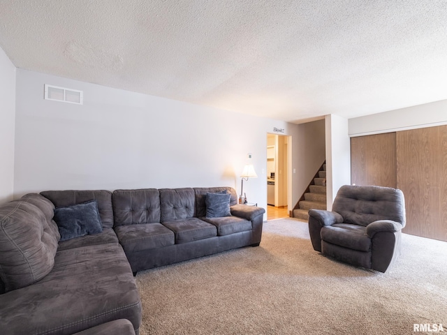 living room with visible vents, a textured ceiling, carpet flooring, and stairs