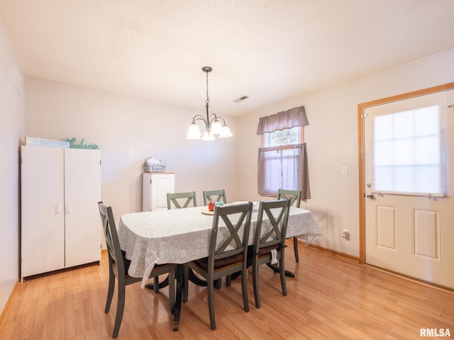 dining area featuring light wood finished floors, visible vents, baseboards, and an inviting chandelier