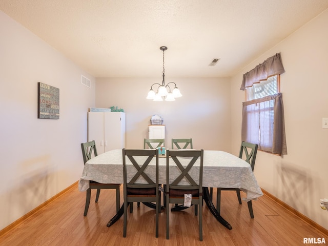 dining area with a notable chandelier, visible vents, and light wood-type flooring