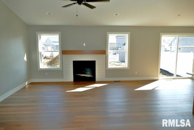 unfurnished living room with baseboards, a ceiling fan, wood finished floors, and a fireplace