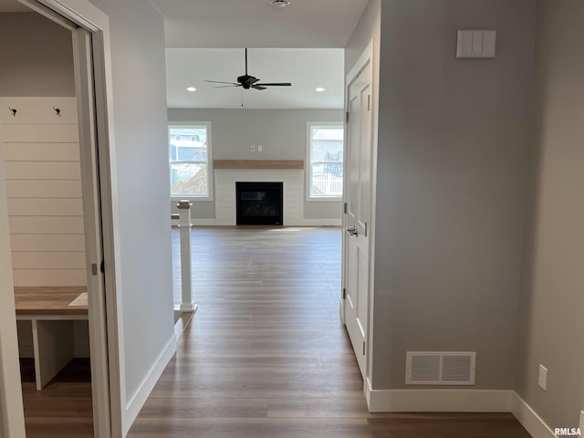 hallway featuring baseboards, visible vents, a wealth of natural light, and wood finished floors