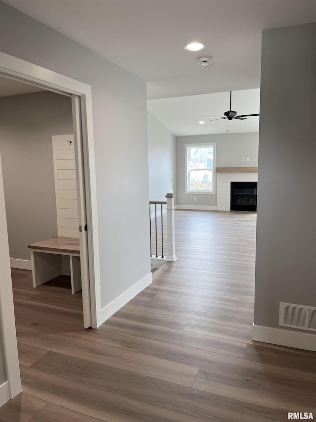 corridor featuring baseboards, wood finished floors, and visible vents