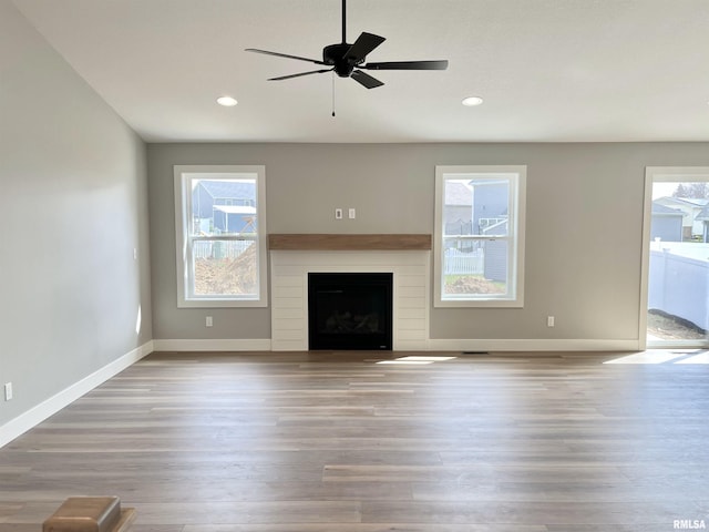 unfurnished living room with a fireplace, recessed lighting, baseboards, a ceiling fan, and wood finished floors