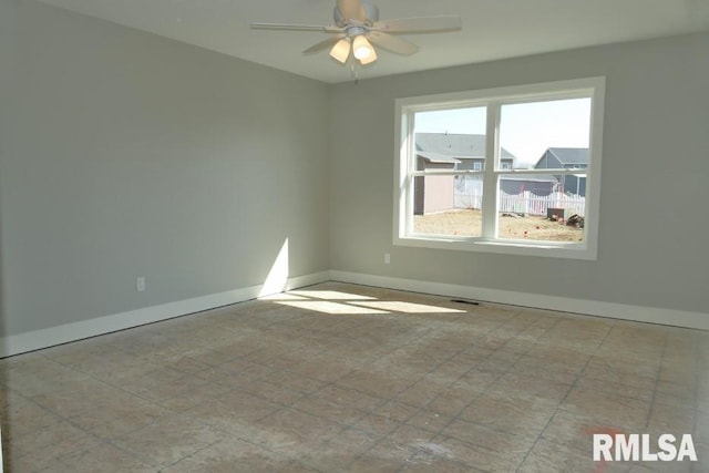 empty room with a ceiling fan and baseboards