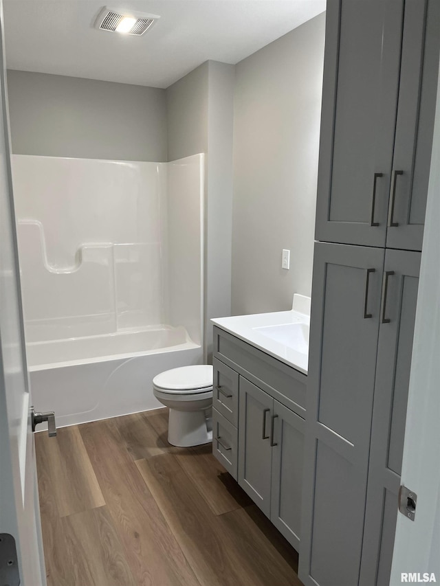 full bathroom with visible vents, wood finished floors, vanity, toilet, and  shower combination