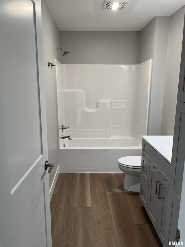 full bath with washtub / shower combination, vanity, toilet, wood finished floors, and visible vents
