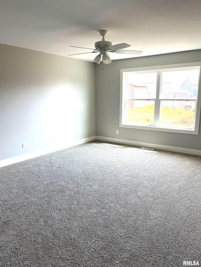 carpeted empty room with ceiling fan, visible vents, and baseboards