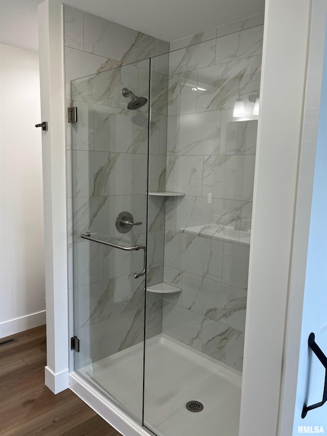 full bathroom featuring baseboards, a stall shower, visible vents, and wood finished floors
