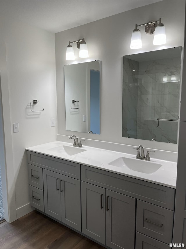 bathroom featuring double vanity, a shower stall, a sink, and wood finished floors