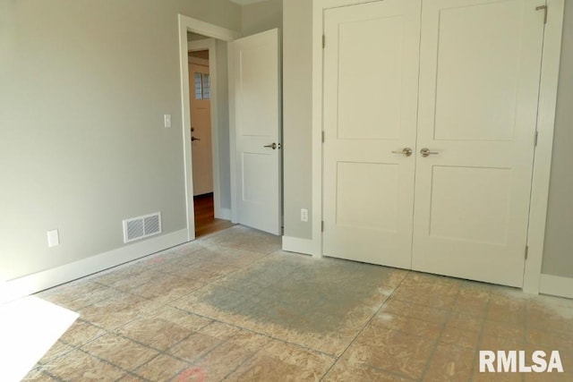 unfurnished bedroom with baseboards, visible vents, and a closet