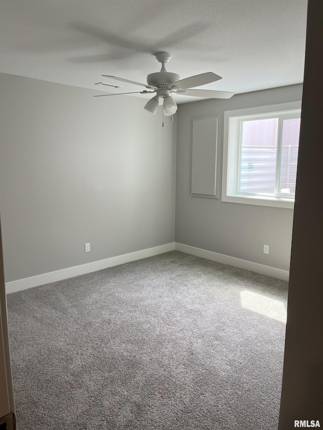 carpeted empty room with a ceiling fan and baseboards