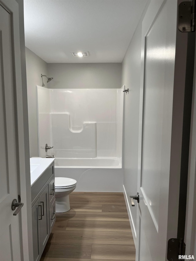 bathroom with visible vents, wood finished floors, vanity, toilet, and shower / bathtub combination