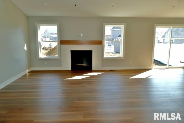 unfurnished living room with recessed lighting, baseboards, wood finished floors, and a fireplace