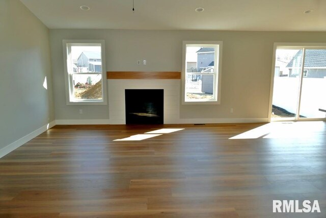 unfurnished living room featuring recessed lighting, baseboards, wood finished floors, and a fireplace