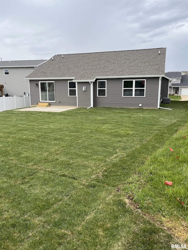 back of house with a patio, a shingled roof, a lawn, and fence
