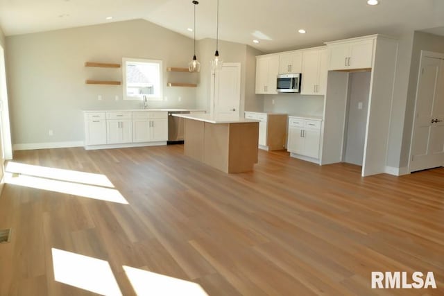 kitchen featuring light wood-style flooring, a kitchen island, appliances with stainless steel finishes, and white cabinets