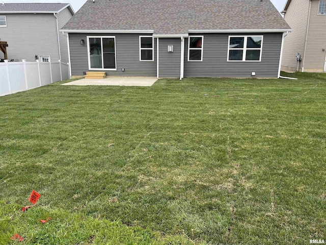 back of property featuring a yard, roof with shingles, fence, and a patio area
