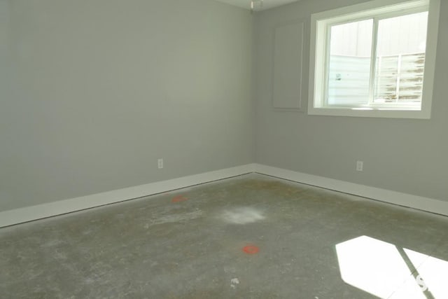 empty room with baseboards and unfinished concrete flooring