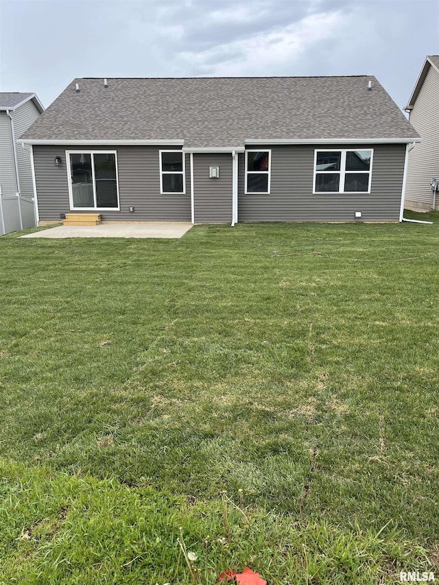 rear view of house featuring a yard, a patio, and roof with shingles