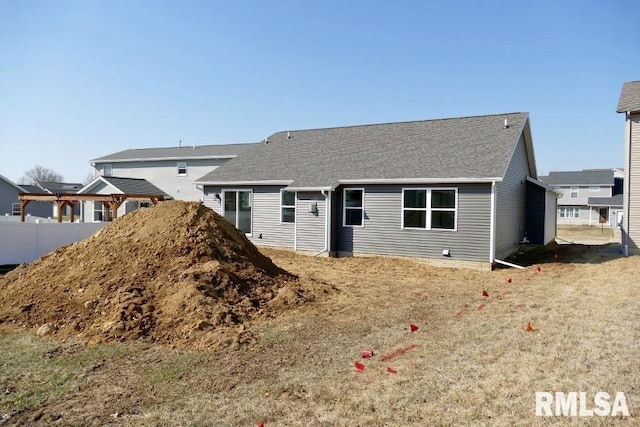 view of front facade featuring fence and a shingled roof