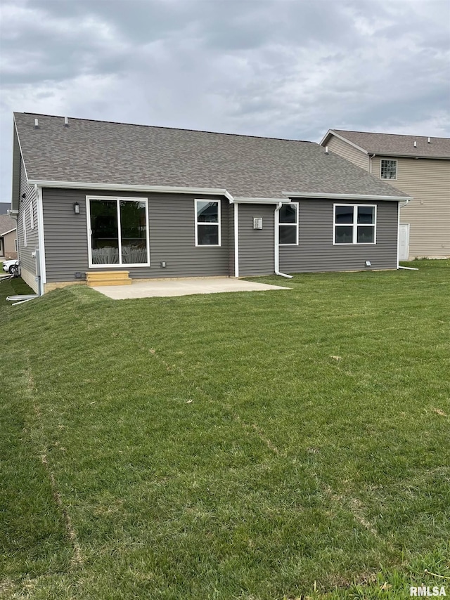 rear view of house with a lawn, a patio, and roof with shingles