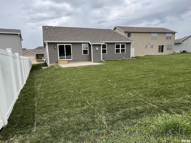 back of property with a lawn, fence, a patio area, and roof with shingles