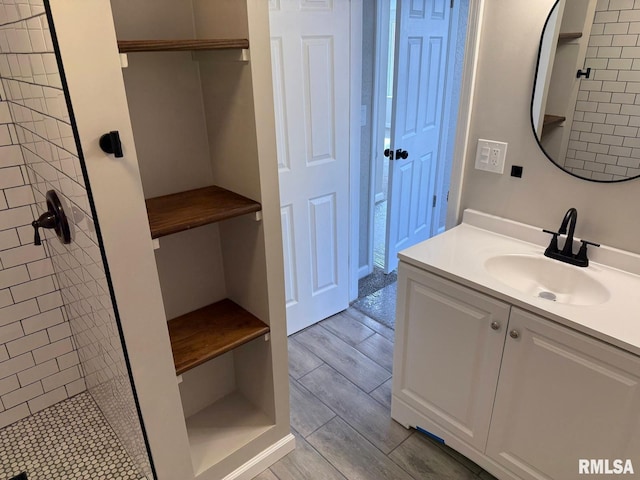 bathroom featuring tiled shower, wood tiled floor, and vanity