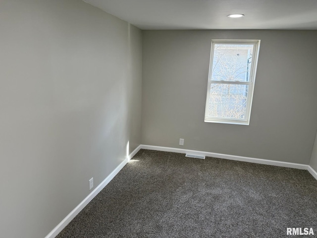 unfurnished room with visible vents, baseboards, and dark colored carpet