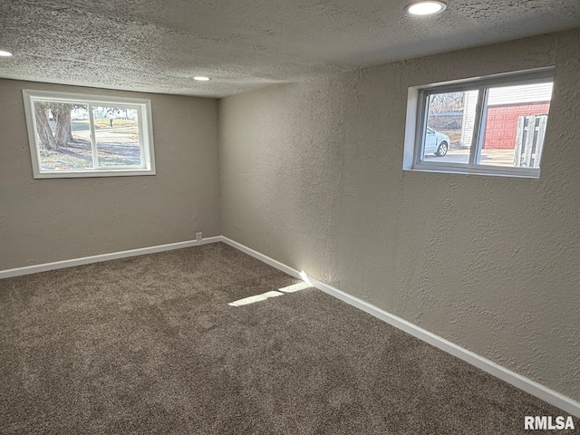 basement with a healthy amount of sunlight, a textured ceiling, carpet, and a textured wall