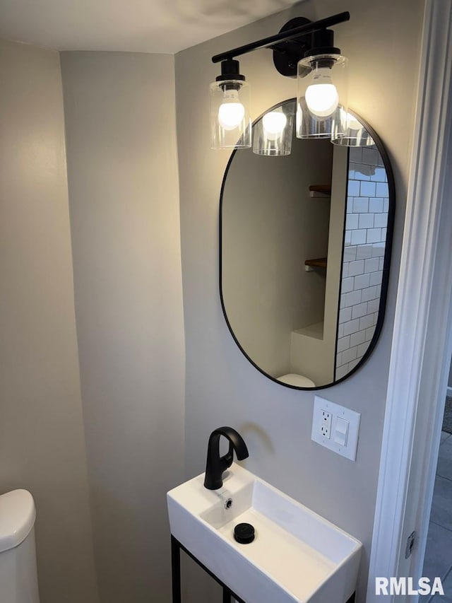 half bath featuring a sink, a notable chandelier, and toilet