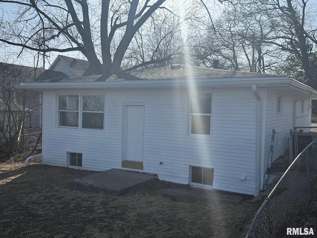 back of property with fence and a shingled roof