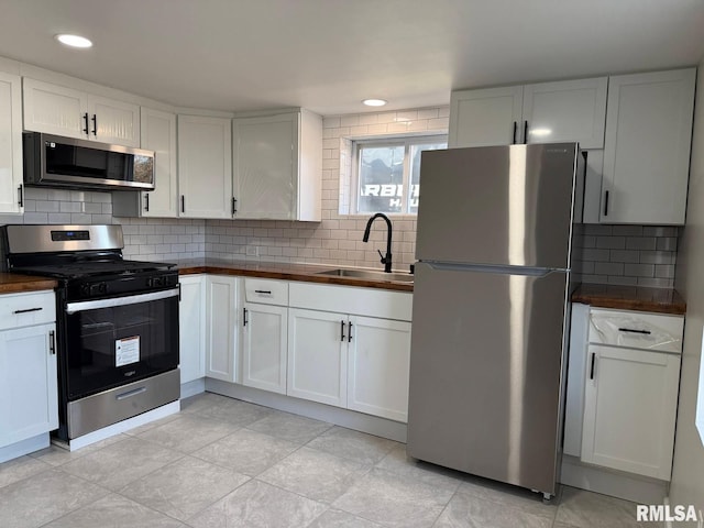 kitchen with a sink, decorative backsplash, butcher block counters, and stainless steel appliances