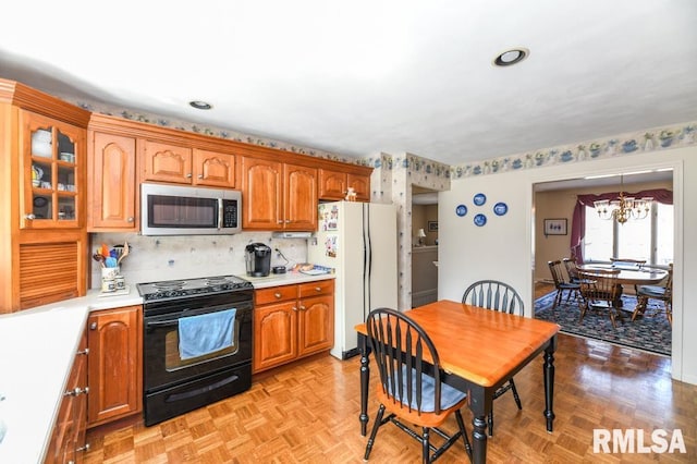 kitchen with an inviting chandelier, freestanding refrigerator, light countertops, black range with electric cooktop, and stainless steel microwave