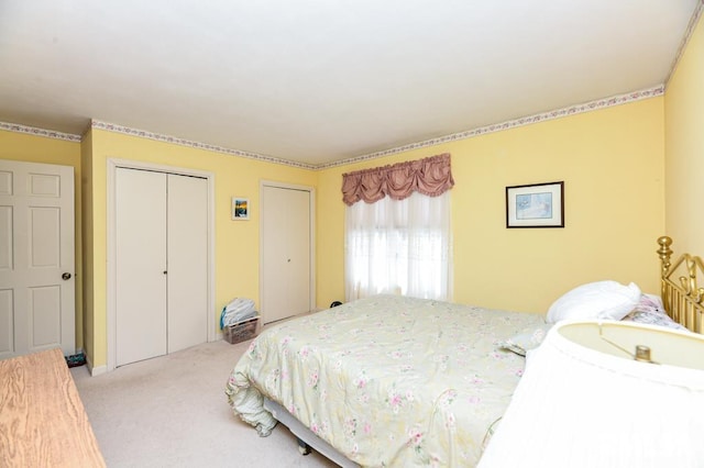 bedroom featuring light colored carpet and multiple closets