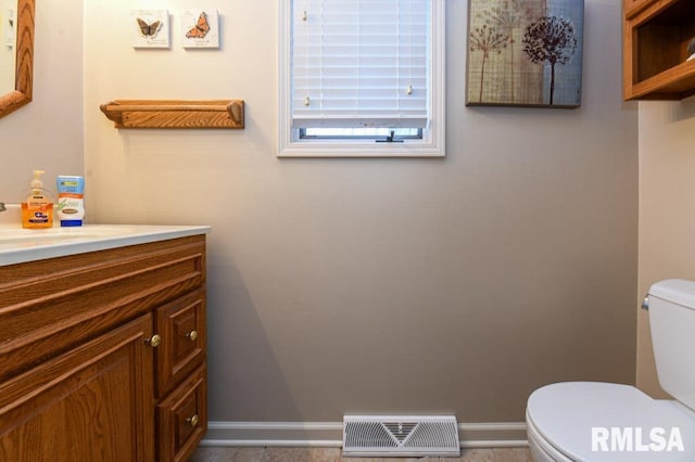 bathroom with visible vents, toilet, vanity, and baseboards