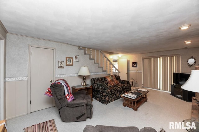 carpeted living area featuring stairway and wainscoting